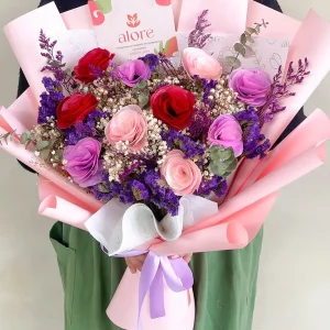 Ramo de flores eternas rosadas, rojas y moradas en papel rosado