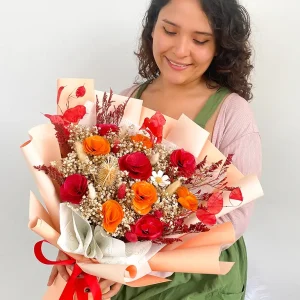 Ramo de flores eternas rojas y naranjas con flores secas en papel durazno