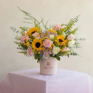 Girasoles, rosas y claveles rosados con follaje en caja Alore