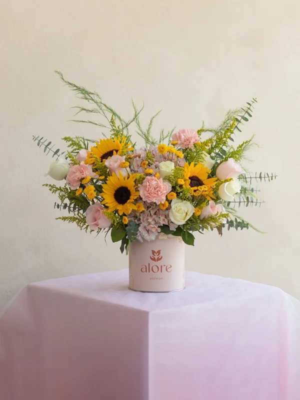 caja_de_flores_amarillas_y_rosadas_premium arreglo floral de girasoles y rosas colocado en una mesa