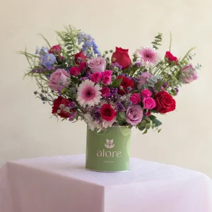 Rosas rojas, gerberas y flores moradas en caja verde Alore