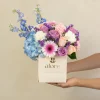 caja_de_flores_lilas_y_celestes_sostenida caja beige con flores azules con moradas