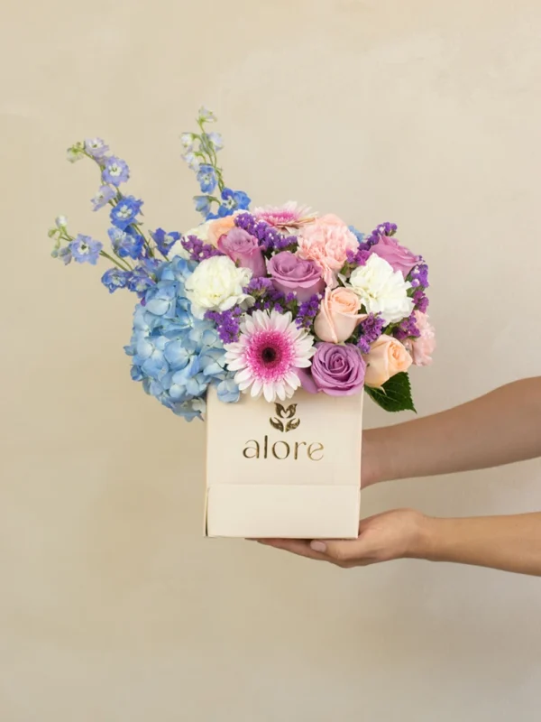 caja_de_flores_lilas_y_celestes_sostenida caja beige con flores azules con moradas