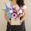 caja_de_flores_lilas_y_melon_con_modelo mujer sosteniendo una caja de flores azules, lilas y blancas