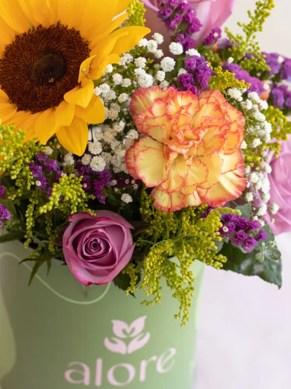 caja verde con flores lilas y amarillas