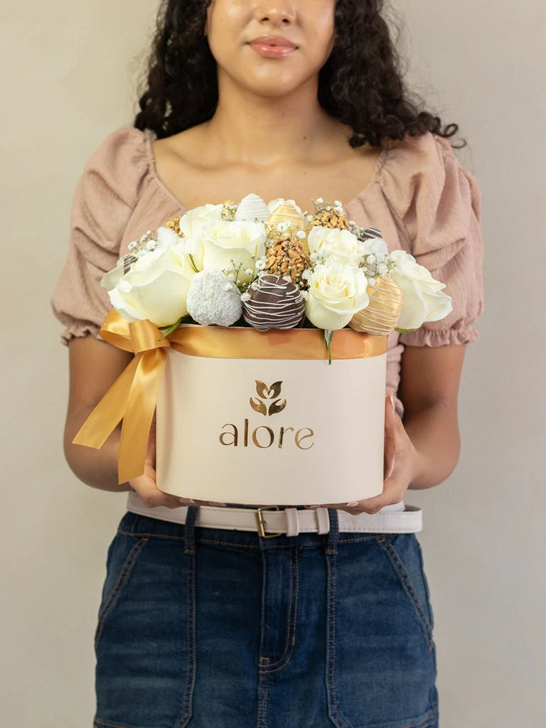 Mujer sosteniendo caja Alore grande con rosas blancas y fresas bañadas en chocolate
