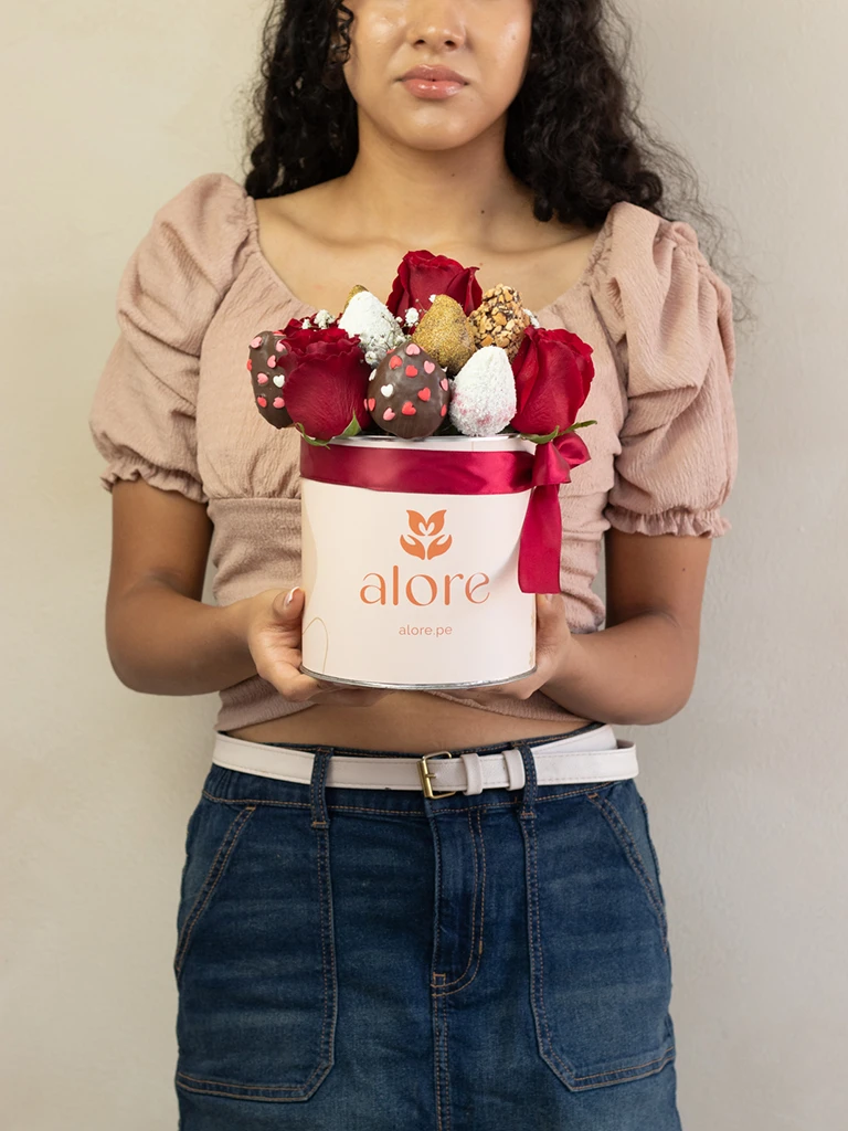 Mujer sosteniendo caja Alore con rosas rojas y fresas bañadas en chocolate