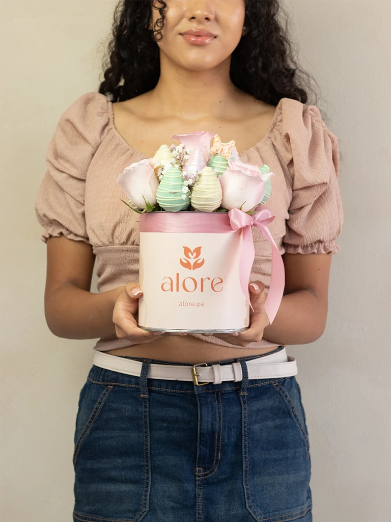 Mujer sosteniendo caja Alore con rosas rosadas y fresas bañadas en chocolate pastel