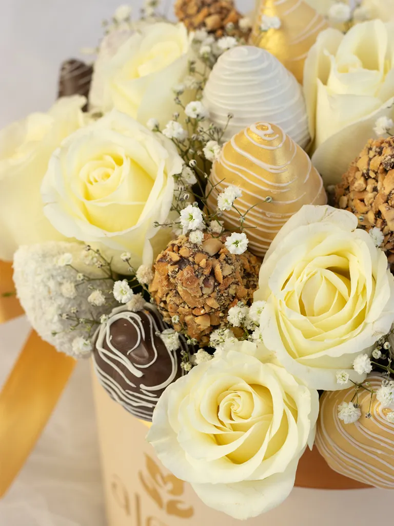 Detalle de rosas blancas con fresas bañadas en chocolate dorado, bitter y maní