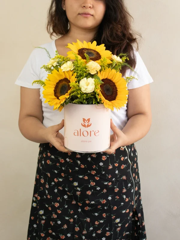 mujer sosteniendo una caja con 5 girasoles de vivero