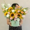 mujer sosteniendo un caja gigante de flores premium en color amarillo, melón y blanco