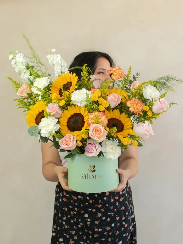 mujer sosteniendo un caja gigante de flores premium en color amarillo, melón y blanco