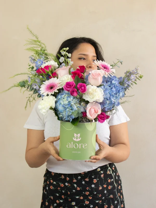 mujer sosteniendo un arreglo floral de color rosado, azul y blanco