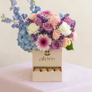 Rosas lilas y durazno, hortensia azul y delphinium en caja cofre con Ferrero Rocher