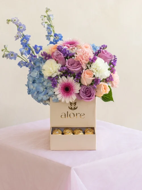 caja_deluxe_con_flores_variadas caja en forma de cofre con rosas azules, melón y lilas . Acompañado de chocolates ferrero rocher