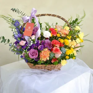 Canasta de mimbre con flores silvestres en tonos morados, amarillos y naranjas