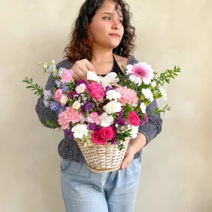 Canasta de mimbre con rosas, claveles y gerberas rosadas y blancas