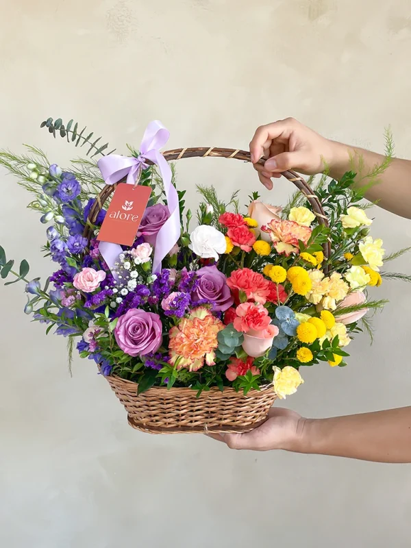 canasta floral tonos primavera manos sujetando una canasta de flores silvestres en tonos amrillos y lilas