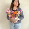 chica con una maceta de flores eternas en colores llamativos