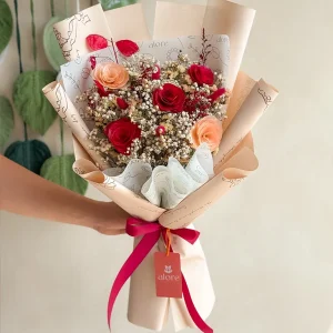 Ramo de rosas rojas y durazno con gypsophila en papel crema