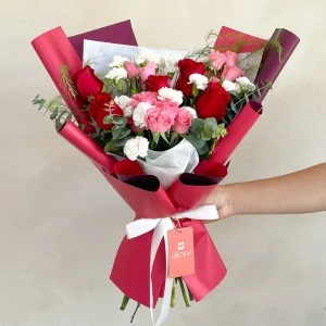 Ramo pequeño de rosas rojas, mini rosas y claveles blancos en papel fucsia