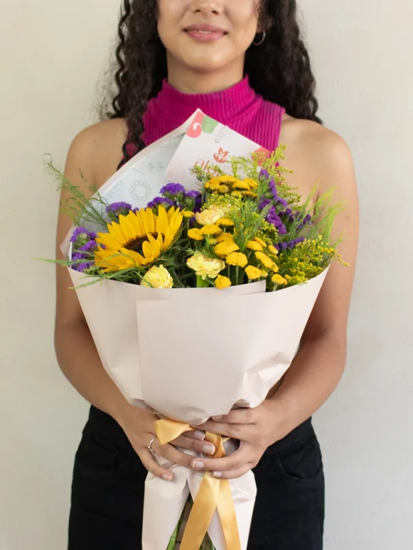 mujer con un ramo de flores variadas en color amarillo