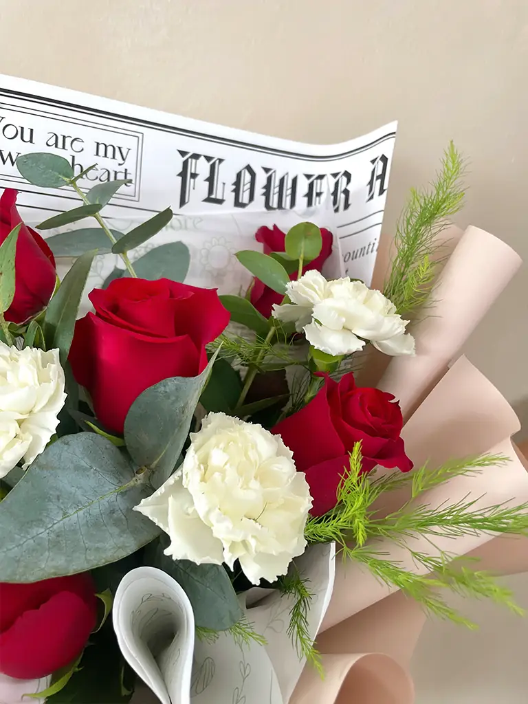 Detalle de rosas rojas y claveles blancos con eucalipto