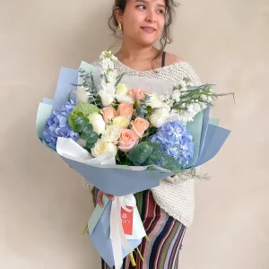 Ramo coreano de hortensias azules, rosas y flores blancas en papel celeste