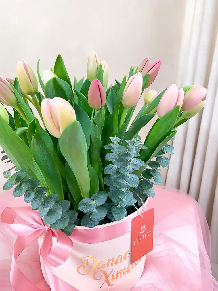 Detalle de tulipanes rosados y blancos con eucalipto en caja personalizada