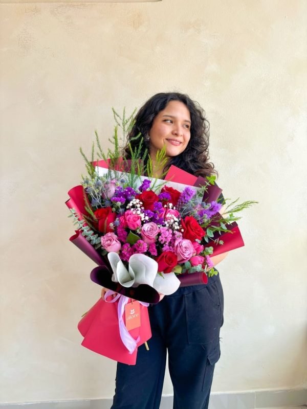 modelo con un ramo grande de flores rojas y moradas