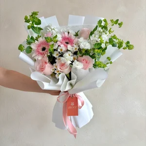 Ramo pequeño de gerberas y rosas rosadas con flores blancas en papel blanco