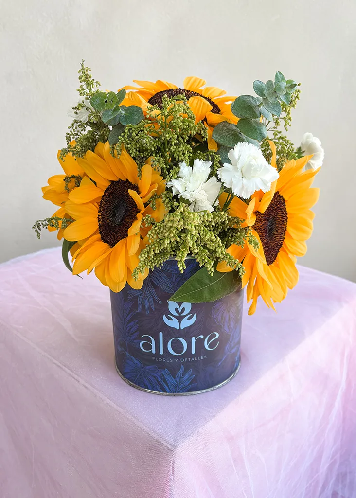 Girasoles con solidago y flores blancas en caja azul Alore sobre mesa