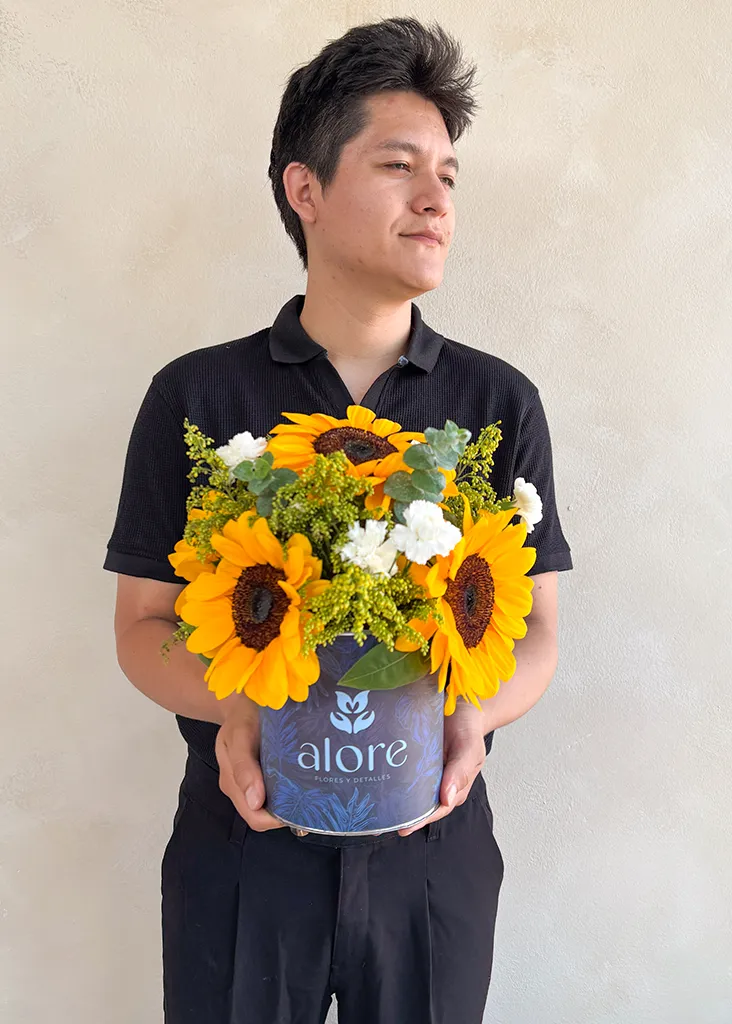 Hombre sosteniendo caja azul Alore con girasoles
