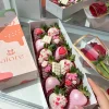 Caja larga con 12 fresas con chocolate y 1 rosa roja en un tocador