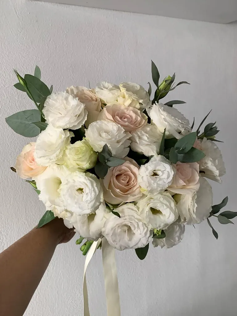 Bouquet de novia de lisianthus blancos y rosas crema con follaje