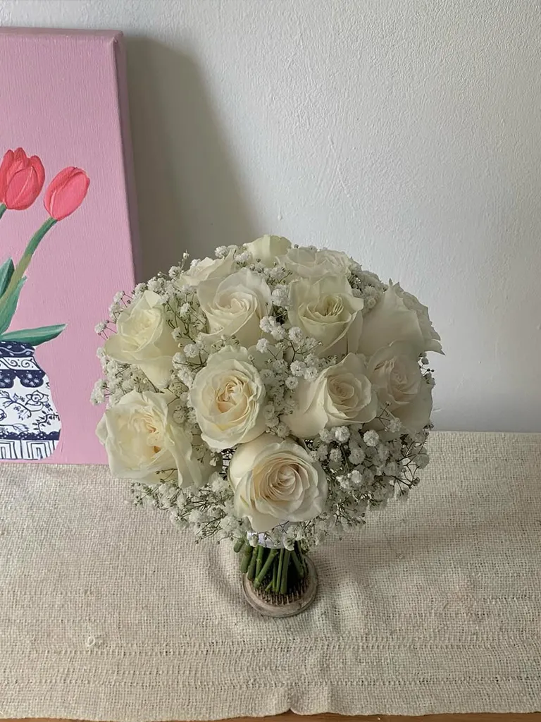 Bouquet de novia de rosas blancas con gypsophila sobre mesa