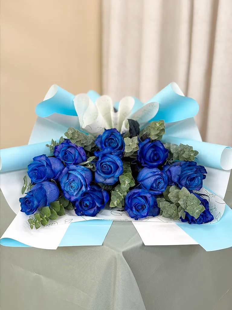 Ramo de rosas azules en papel celeste sobre mesa