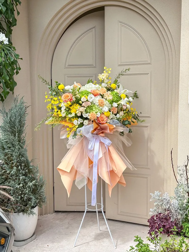 Arreglo floral de pedestal en tonos naranjas y amarillos para inauguración