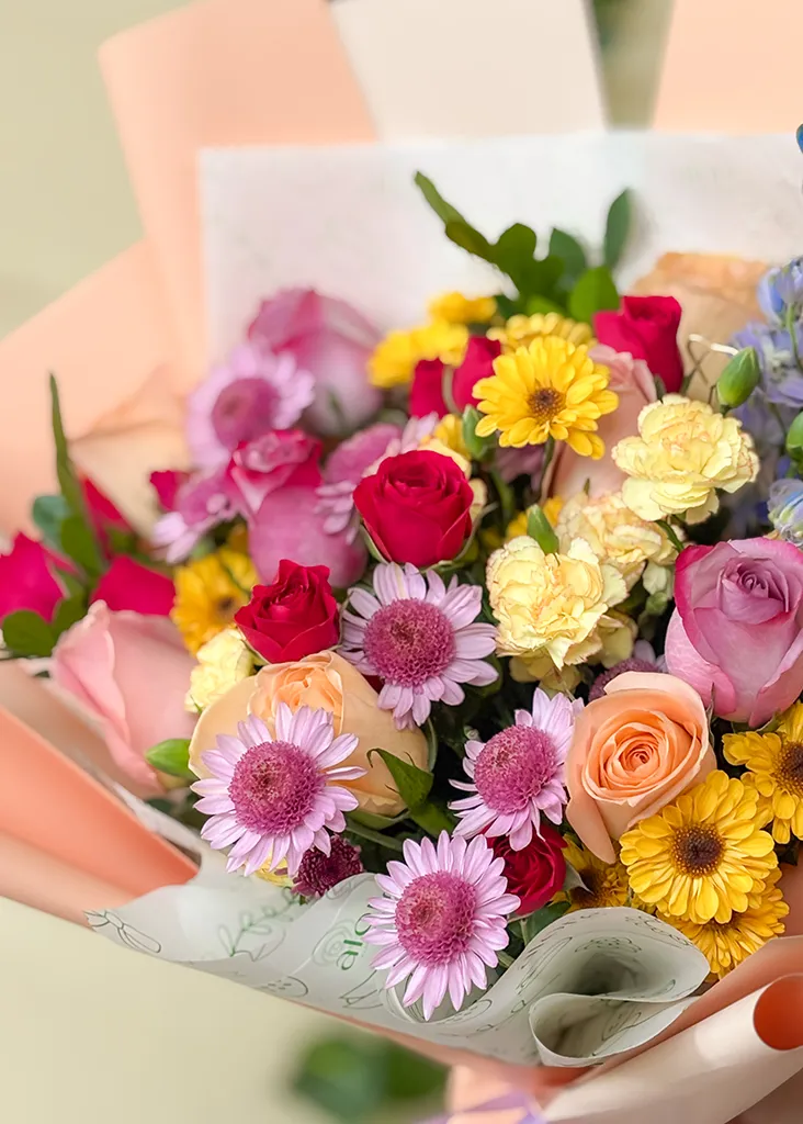 Detalle de rosas, gerberas y crisantemos de colores en papel durazno