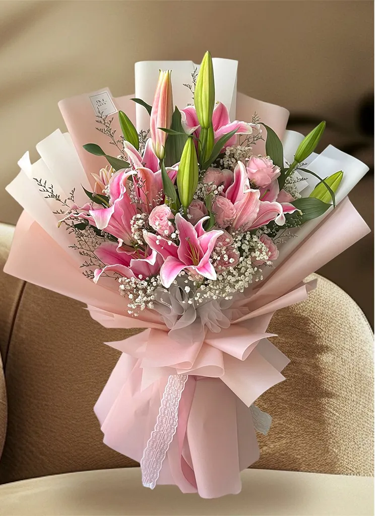Ramo de liliums rosados con rosas y gypsophila en papel rosado