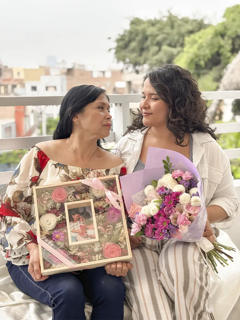 Madre e hija con cuadro de flores eternas y ramo de flores lilas