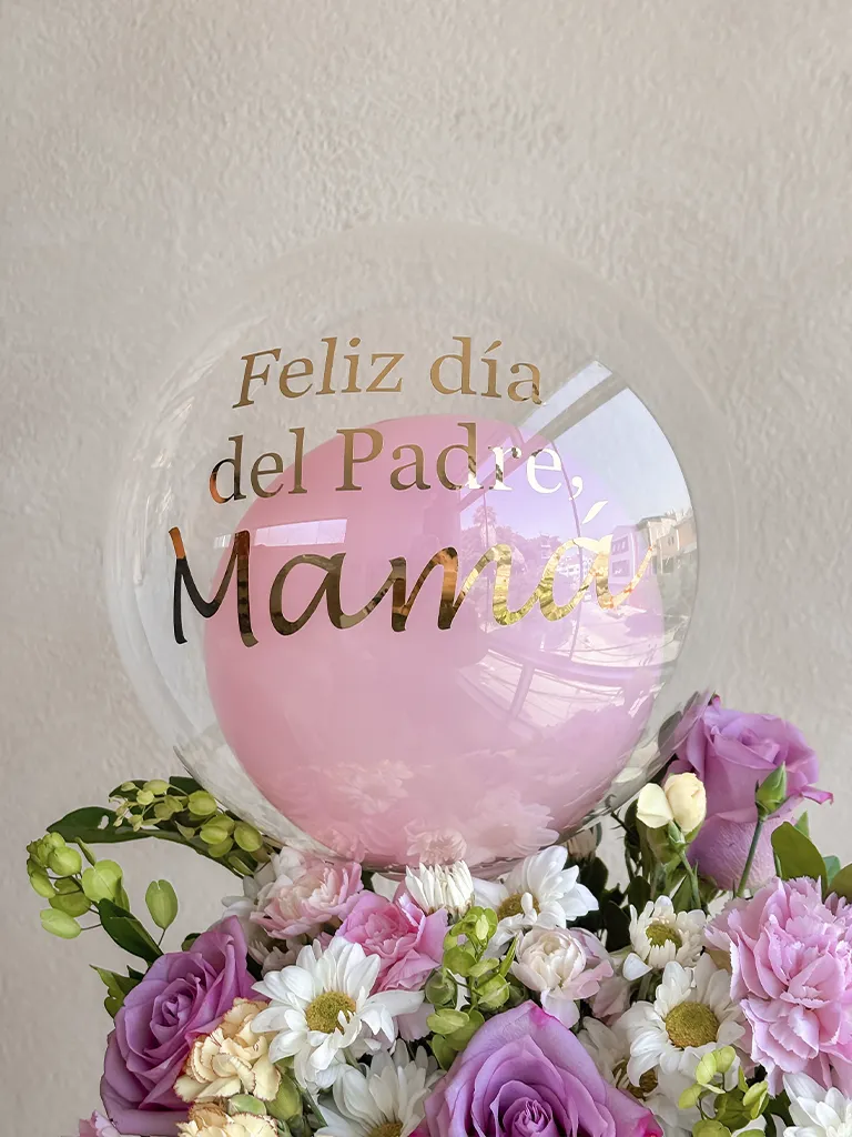Detalle de globo "Feliz día del Padre, Mamá" sobre rosas lilas y margaritas